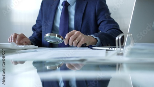 Obraz na płótnie Businessman analyzing financial data with magnifying glass and calculator, conducting audit or review in office. Audit and taxes theme in business w salonie