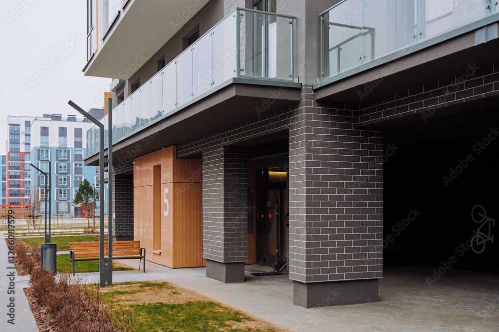 Modern apartment building with a contemporary design featuring a combination of glass, wood, and dark brick. Wooden panel indicates the entrance Modern apartment building with a contemporary design featuring a combination of glass, wood, and dark brick. Wooden panel indicates the entrance