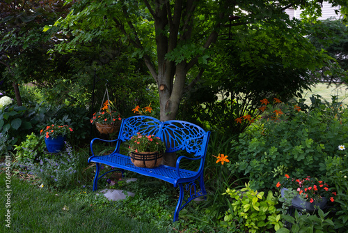 The cobalt blue bench stands freshly transformed, its surface gleaming with a fresh smooth coat of glossy spray paint, inviting visitors to sit and admire the beauty of the vibrant flowers in garden.