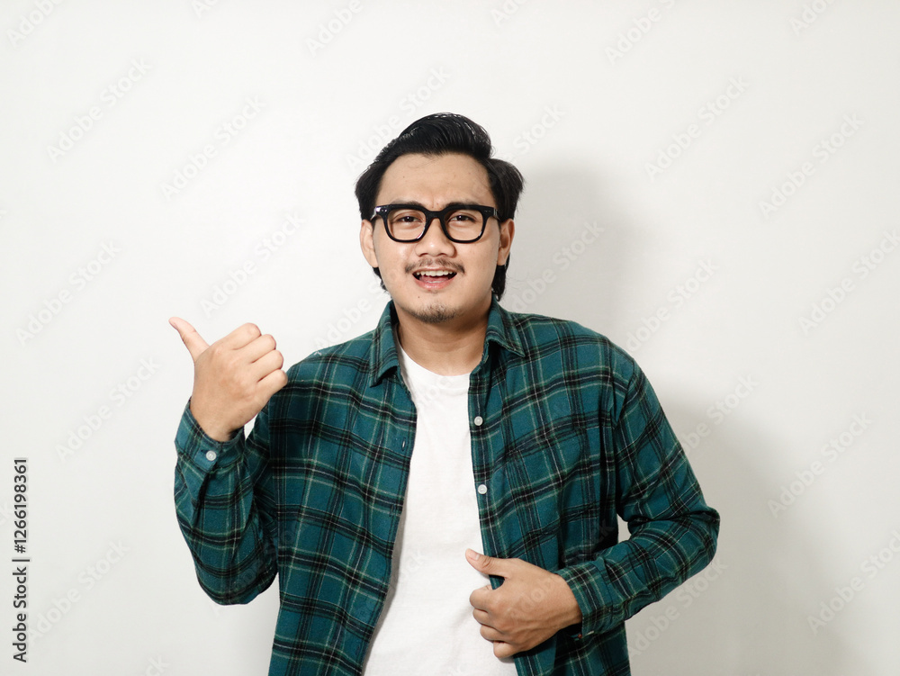 Smiling young handsome Asian man wearing a plaid shirt pointing finger at empty copy space isolated on white background Smiling young handsome Asian man wearing a plaid shirt pointing finger at empty copy space isolated on white background
