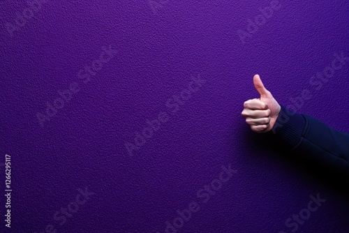 Hand giving a thumbs up against a purple background photo