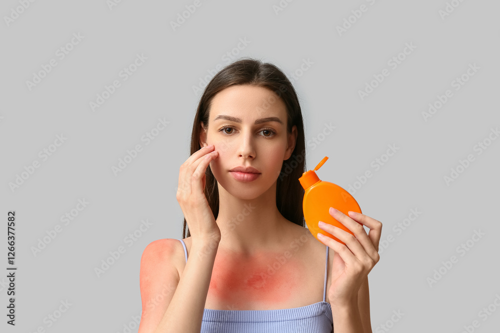 Beautiful young woman with red sunburned skin applying cream on grey background Beautiful young woman with red sunburned skin applying cream on grey background