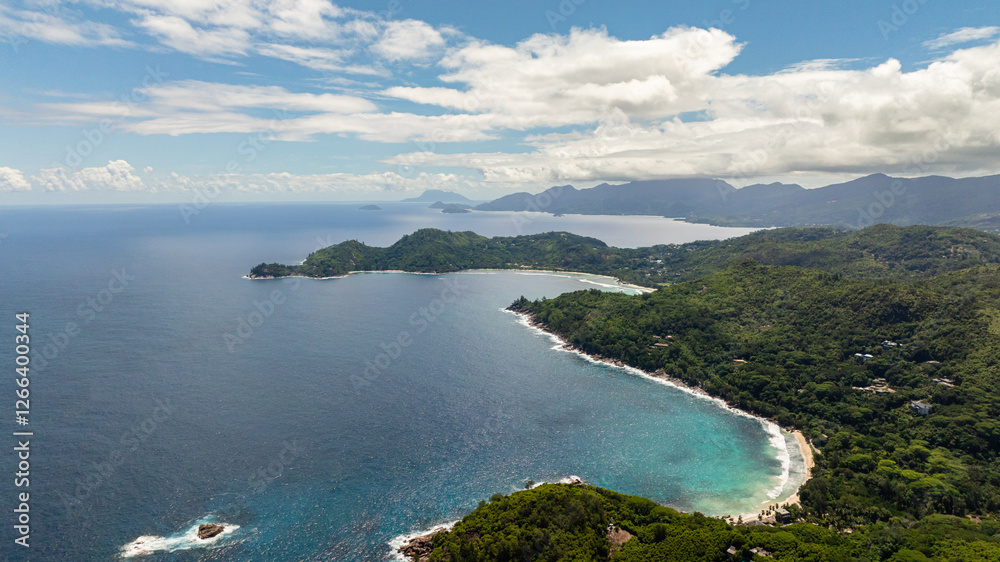 Panoramic view of a lush coastline with hills and turquoise waters under a blue sky. Seychelles, Mahe. Panoramic view of a lush coastline with hills and turquoise waters under a blue sky. Seychelles, Mahe.