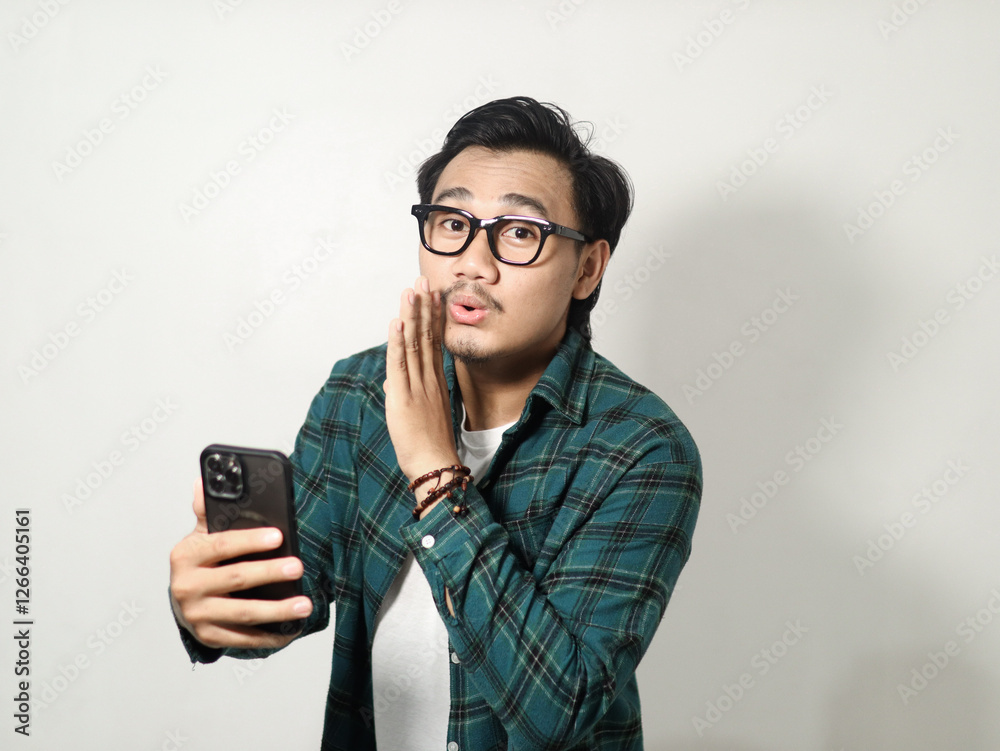 A man whispering something with happy expression while holding mobile phone isolated on white background A man whispering something with happy expression while holding mobile phone isolated on white background