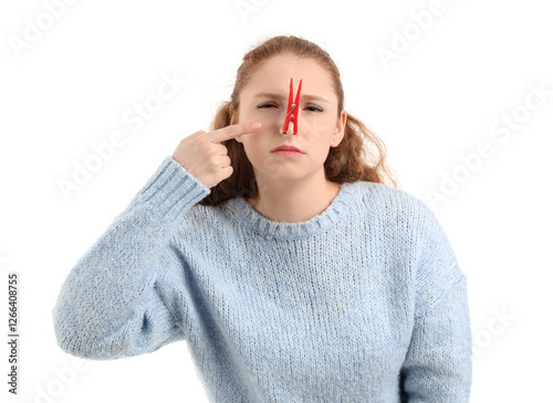 Ill young woman pointing at clothespin on her nose against white background. Stuffy nose concept