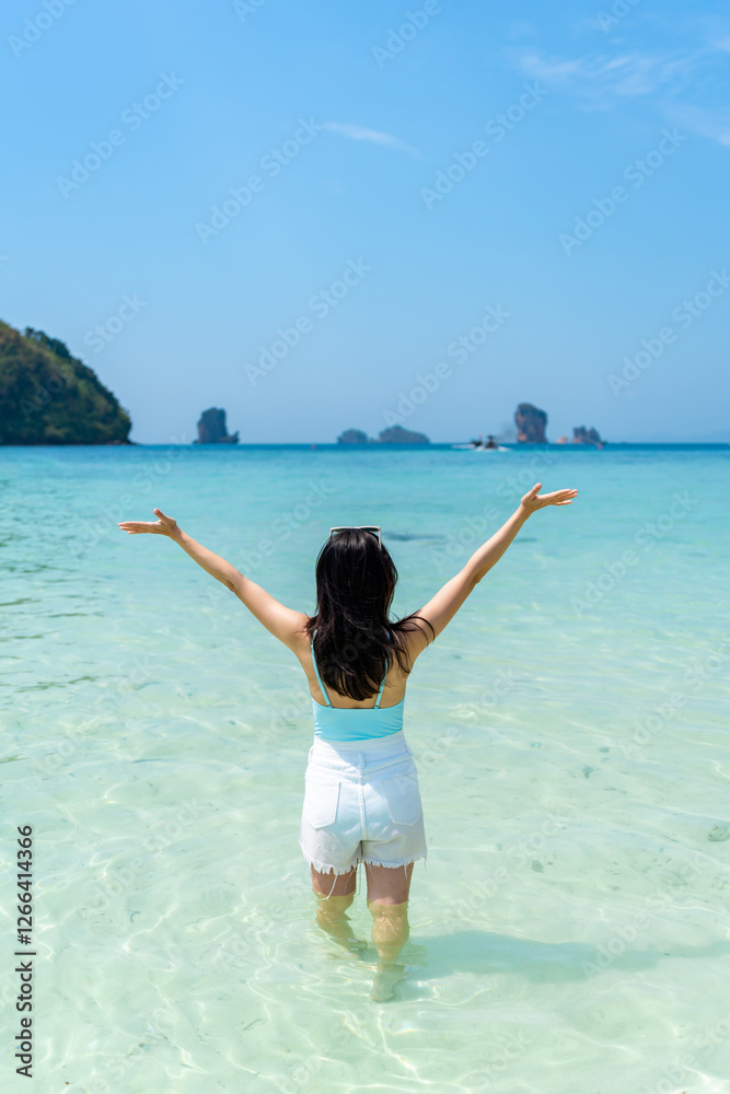 Young Asian woman relaxing and enjoying at beautiful white sand beach on sunny day, Travel on summer vacation