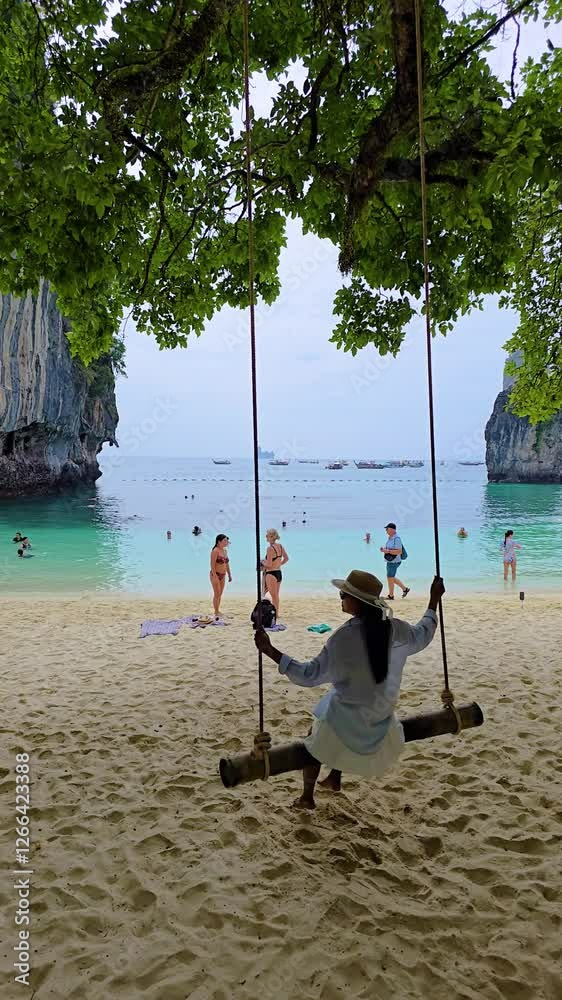 Relaxation unfolds as a woman gentle swing sways beneath lush trees, with sunbathers enjoying picturesque Koh Hong Island Krabi Thailand. Clear waters and towering cliffs provide a stunning backdrop. Relaxation unfolds as a woman gentle swing sways beneath lush trees, with sunbathers enjoying picturesque Koh Hong Island Krabi Thailand. Clear waters and towering cliffs provide a stunning backdrop.
