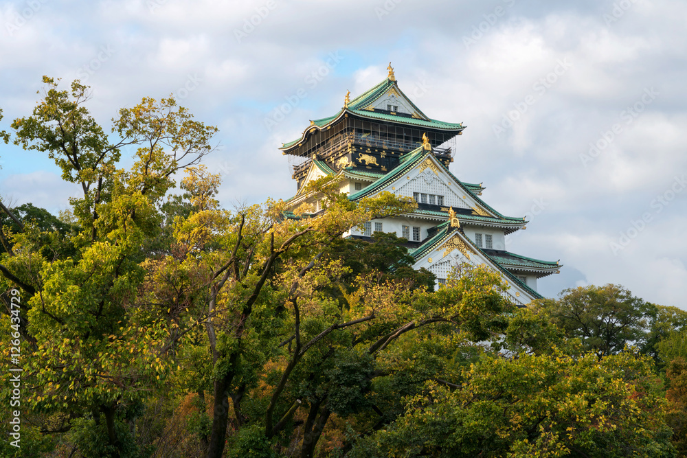 The main tower of Osaka Castle on the background of the golden autumn leaves on a sunny autumn morning, Osaka, Japan The main tower of Osaka Castle on the background of the golden autumn leaves on a sunny autumn morning, Osaka, Japan