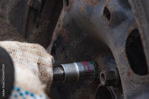 Changing a wheel. Close-up of loosening and tightening wheel bolts. Seasonal tire change. Part of the photo is blurred. The process of changing a car wheel. Close-up.