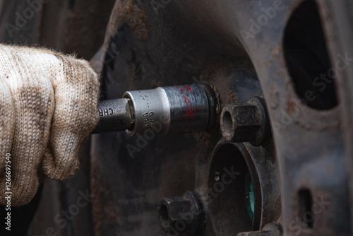 Changing a wheel. Close-up of loosening and tightening wheel bolts. Seasonal tire change. Part of the photo is blurred. The process of changing a car wheel. Close-up.