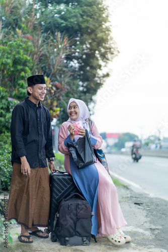asian muslim couple with suitcase prepare to go. concept of man and woman travelling for eid mubarak celebration