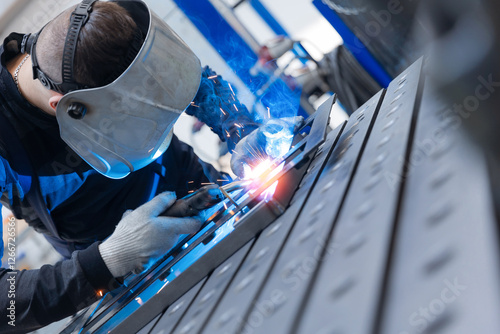 Male worker welding metal in industrial factory setting