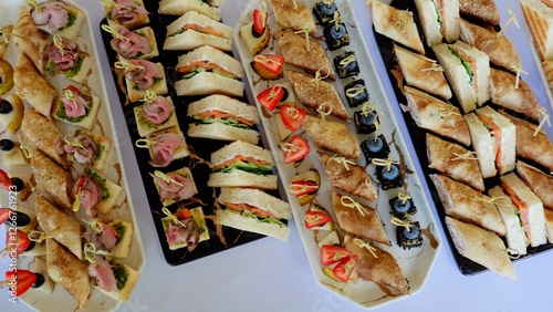 Fotografie Varied platters holding delicate mini sandwiches, rolled crepes, and canapes, pr