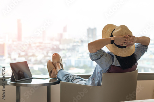Work-Life balance, life quality, work and travel concept with business woman relaxing sitting in rest, take it easy in modern hotel guest room or luxury home living room with notebook and city view