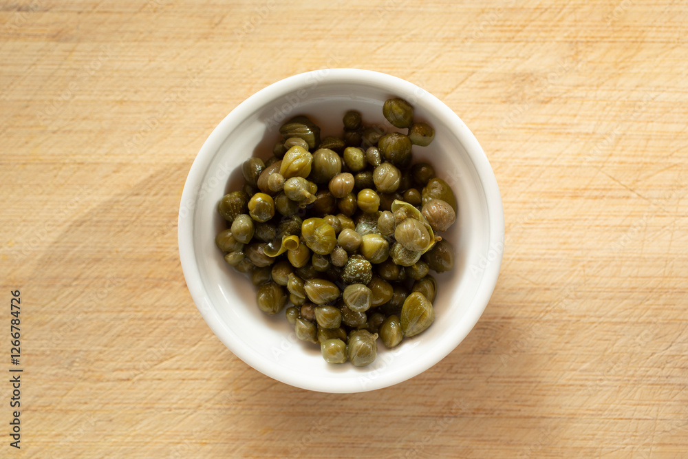 A top down view of a condiment cup of capers. A top down view of a condiment cup of capers.