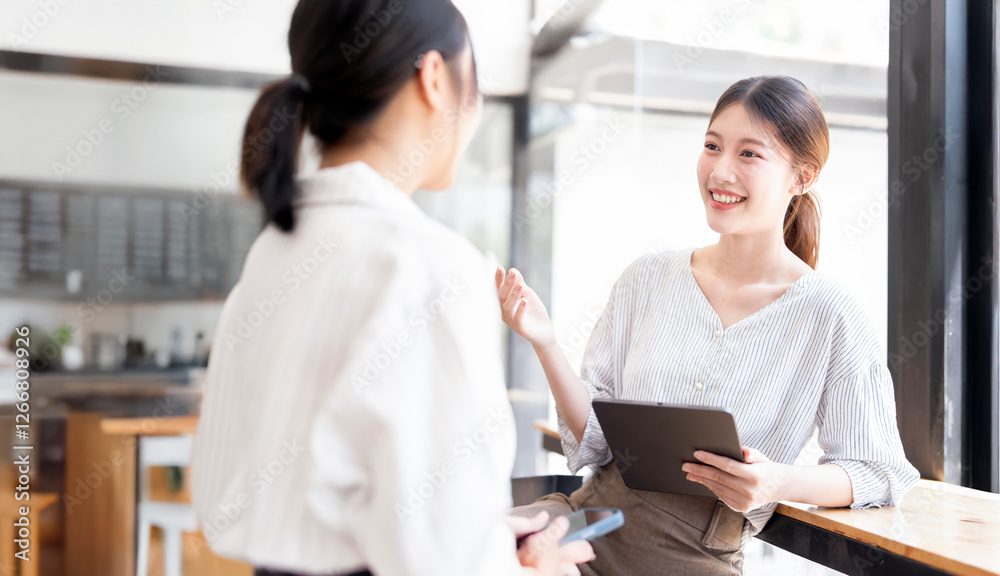 Two young lady colleagues discussing new project, businesswomen using digital tablet together in office Two young lady colleagues discussing new project, businesswomen using digital tablet together in office