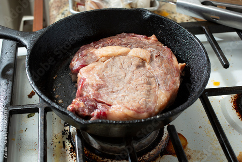 A view of a ribeye steak in a cast iron skillet. photo