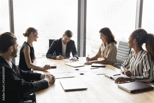 Group of diverse business partners, stakeholders signing contracts sit at table in office, put signatures on legal documents papers after successful negotiations, establish partnership, make agreement