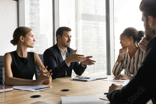 Group of business professionals gathered in modern board room, engaged in serious discussion, strategizing, making important decisions, consider new business project details, budget or issue solution