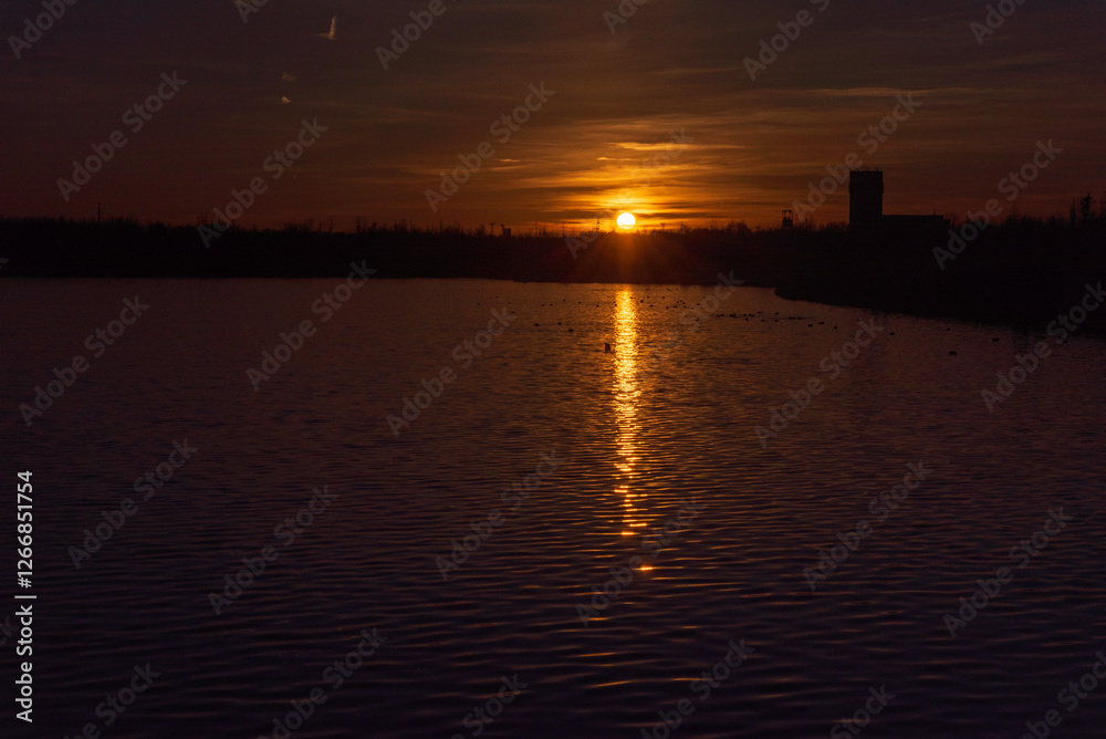 Sunset with orange sky on Karvinske more lake in Karvina city in Czech republic Sunset with orange sky on Karvinske more lake in Karvina city in Czech republic