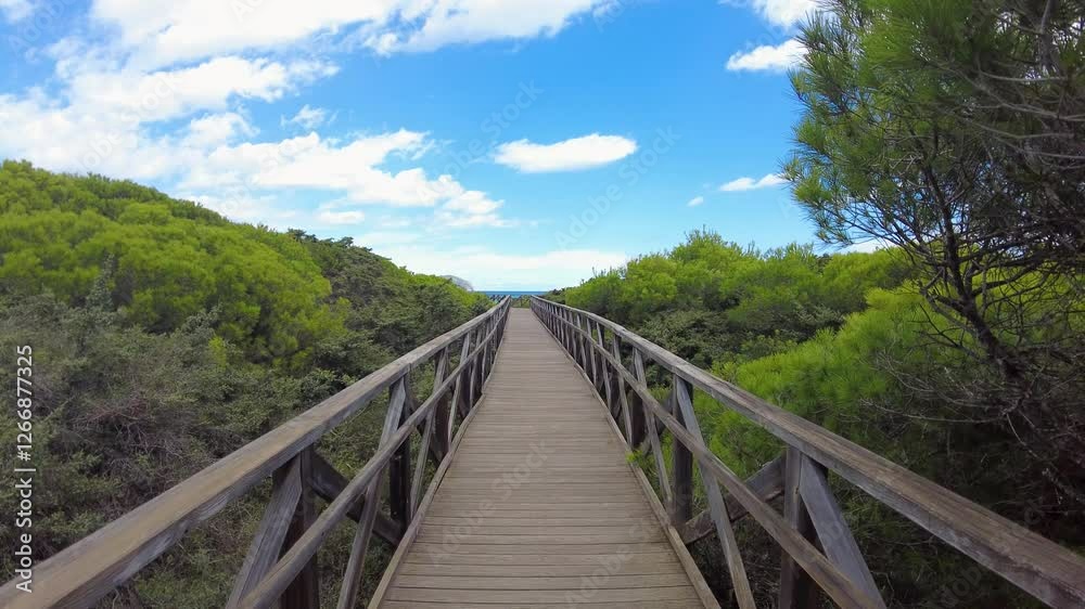 Walking across a Pedestian Bridge in Alcudia, at Playa del Muro Beach in Mallorca, Spain Walking across a Pedestian Bridge in Alcudia, at Playa del Muro Beach in Mallorca, Spain