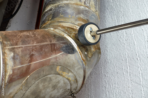 Heating pipe with a probe of a measuring device. Soot and carbon monoxide is tested. Closeup. (BIMSCH and EEG)