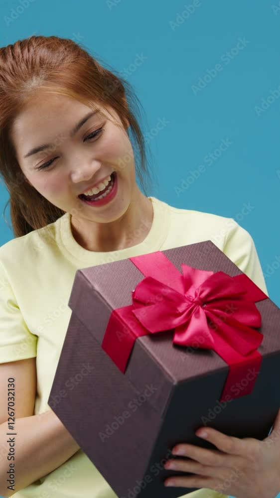 Vertical Screen : Young Asia girl smile holding opened present box isolated over blue background. Copy space for place a text, message for advertisement. Advertising area, mockup promotional content. Vertical Screen : Young Asia girl smile holding opened present box isolated over blue background. Copy space for place a text, message for advertisement. Advertising area, mockup promotional content.