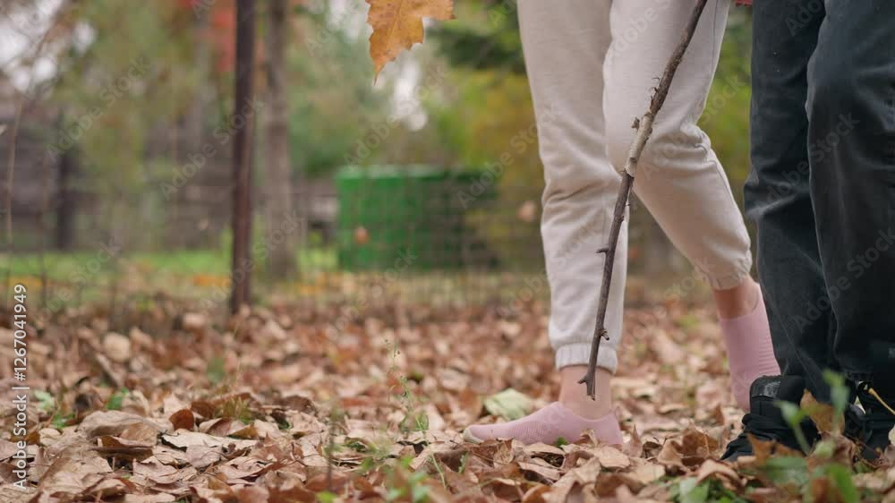 Leg view of two people walking through dry autumn leaves in an outdoor setting, highlighting movement, connection with nature, and the crunching sound of foliage underfoot Leg view of two people walking through dry autumn leaves in an outdoor setting, highlighting movement, connection with nature, and the crunching sound of foliage underfoot