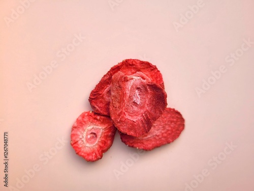 Little pile of dried strawberries on a pink background.