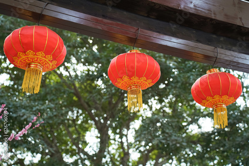 Obraz na płótnie red lanterns hang from wooden deck isolated with green tree leaves as background w salonie