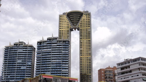 Timelapse of the Intempo Skyscraper in Benidorm, Spain Tallest Building in Costa Blanca golden tower bottom Street View with houses in front of the tower 
and Blue cloudy Sky clouds moving fast 4K HQ