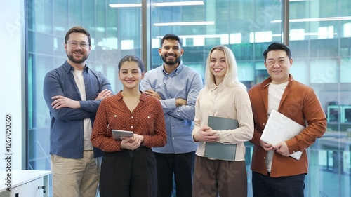 Portrait of group happy multiethnic team standing in modern office. Successful corporate colleague workers posing looking at camera smiling. Teamwork of confident professional leaders and employees