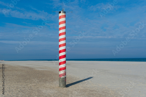 Striped Navigation Pole on a Sandy Beach with Blue Sky and Sea in Jastrzębia Góra