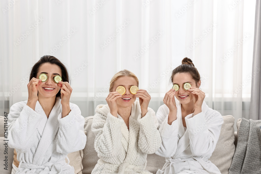 Happy women with cucumber slices on sofa in spa Happy women with cucumber slices on sofa in spa