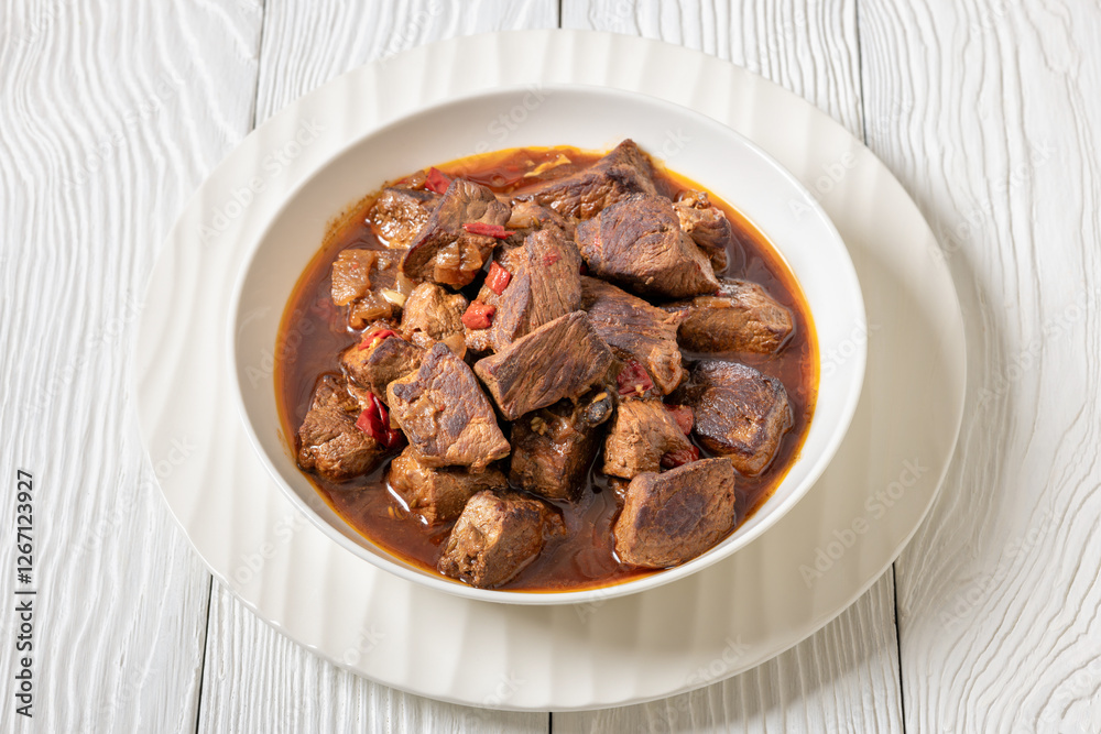 beef stew in a white bowl on rustic wooden table
