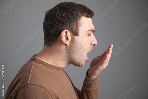 Картината върху платно Man checks his breath with his hand. The concept of halitosis