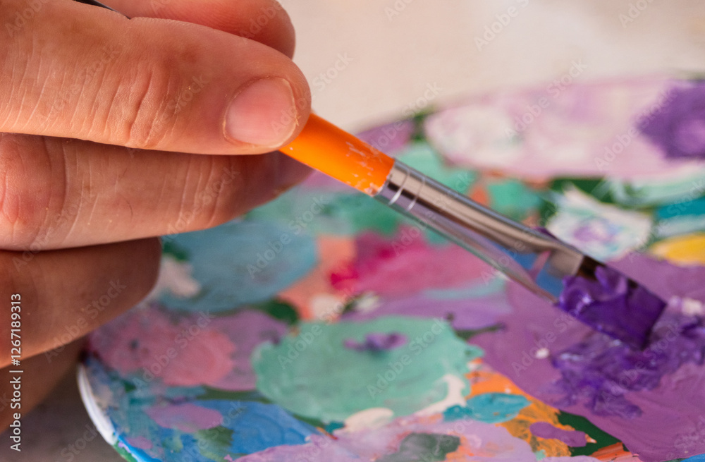 Obraz premium Hand holding a brush and creating colors on his palette.