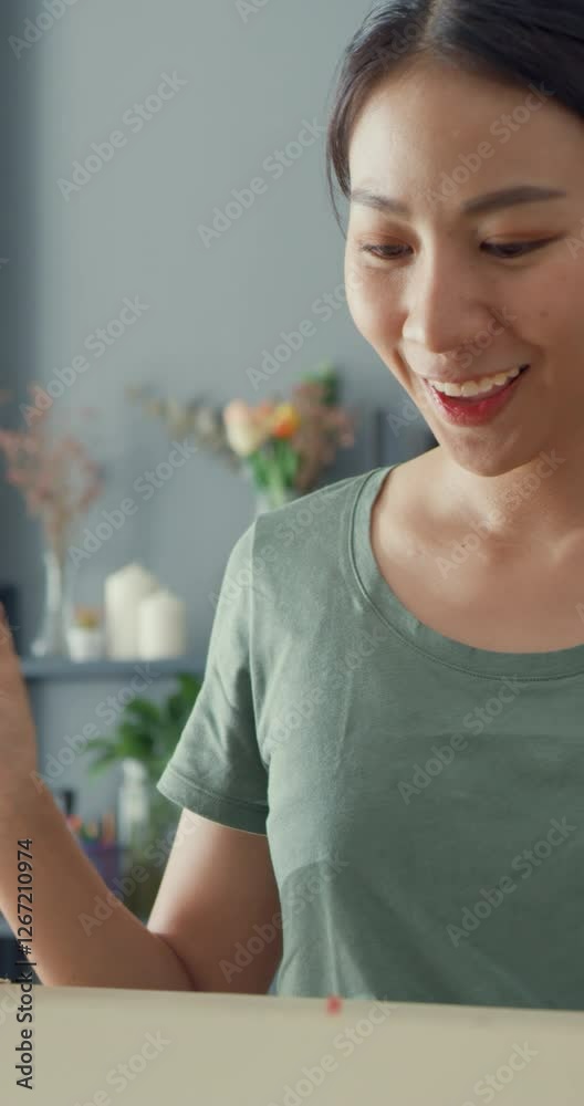 Vertical Screen : Happy Asia lady unboxing cardboard delivery package from online marketplace in living room at house. Satisfied shopper in internet unboxing goods, Online shopping delivery concept.