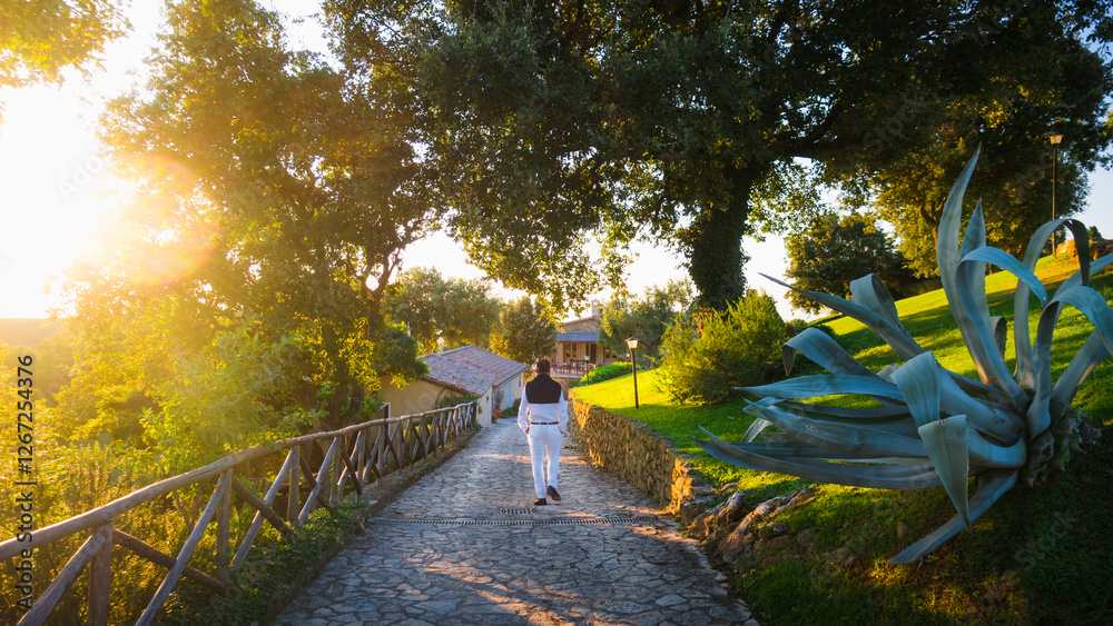 Obraz premium A men dressed in old money style walks to the villa in italy during golden hour on Tuscany countryside with beautiful sunlight evokes dolce vita, slow life and relax far from hustle