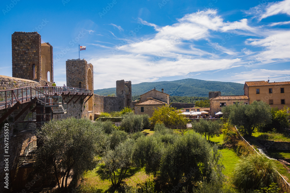 Obraz premium Medieval walls in the small town somewhere in Tuscany during summer day with olives trees and hills on the background forms typical stereotypes of italian countryside when travelling Europe
