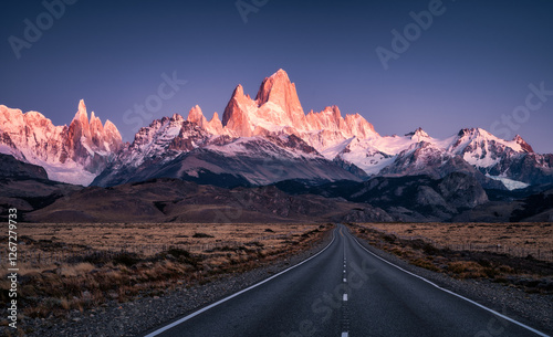Stunning view of Mount Fitz Roy and Cerro Torre snowcapped steep walls enlightened in red color by morning sun seen from the road to El Chalten, Patagonia, Argentina.