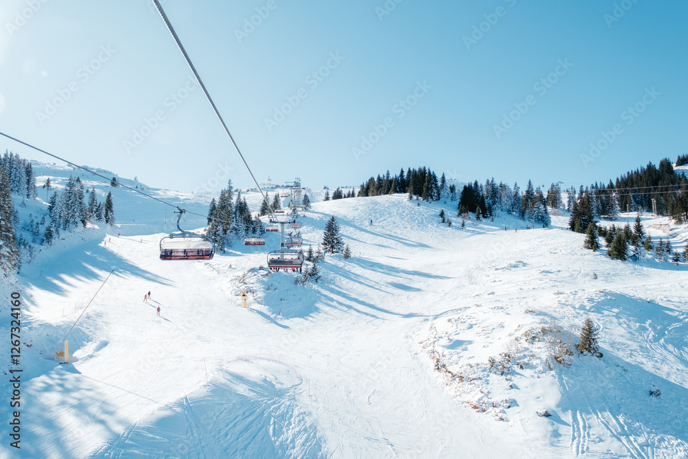 Ski Resort Scene: Chairlift over snowy slopes with skiers trees and a clear blue sky above Winter day Ski Resort Scene: Chairlift over snowy slopes with skiers trees and a clear blue sky above Winter day