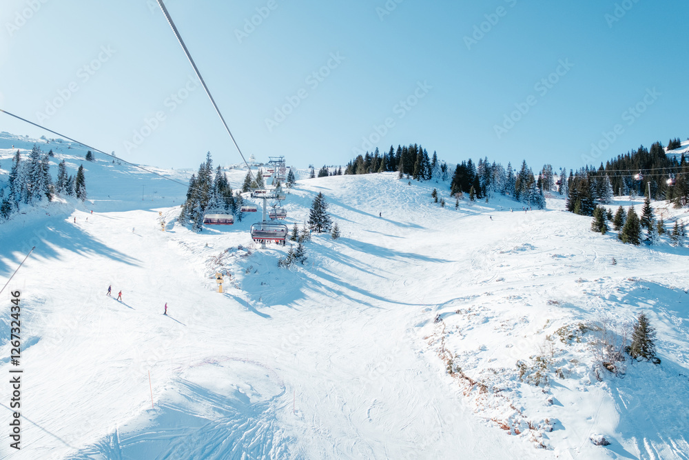Snowy mountain ski resort with chairlift and skiers enjoying the fresh powder on a sunny day Snowy mountain ski resort with chairlift and skiers enjoying the fresh powder on a sunny day