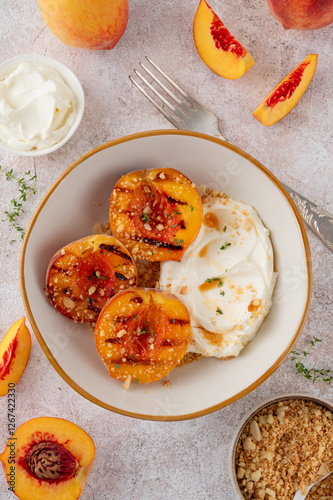 Delicious grilled peaches with mascarpone cream, honey syrup, crumbs and thyme in a bowl on a concrete background. Summer dessert. Top view.