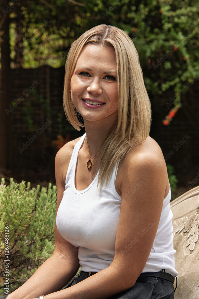 Blonde woman smiling outdoors, casual portrait, garden setting home Blonde woman smiling outdoors, casual portrait, garden setting home