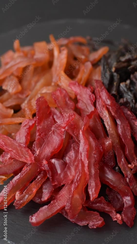 Jerky, dried chicken slices with salt and spices on a dark concrete background Jerky, dried chicken slices with salt and spices on a dark concrete background