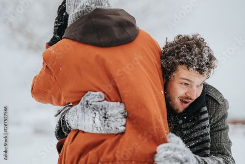 Quadro em tela Two friends enjoying the wintery outdoors while warmly embracing, with joy and laughter amid a snowy atmosphere conveying friendship, warmth, and the essence of seasonal fun