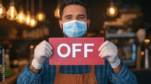 A masked barista holds a sign that says 'OFF' in a cozy coffee shop, reflecting current challenges in the hospitality industry. photo