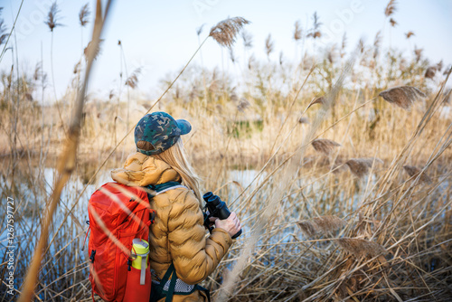 Woman naturalist is watching birds with binoculars. Observation wildlife animals in wetland