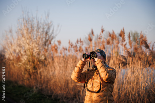 Bird watching. Woman biologist with binoculars observes wildlife animals and water birds in nature habitat